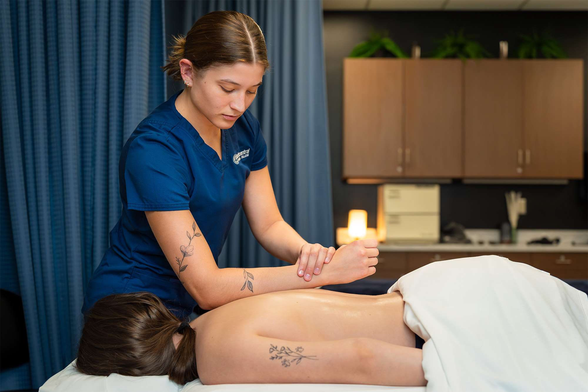 A massage therapist uses her elbow and forearm to massage the back of a patient.
