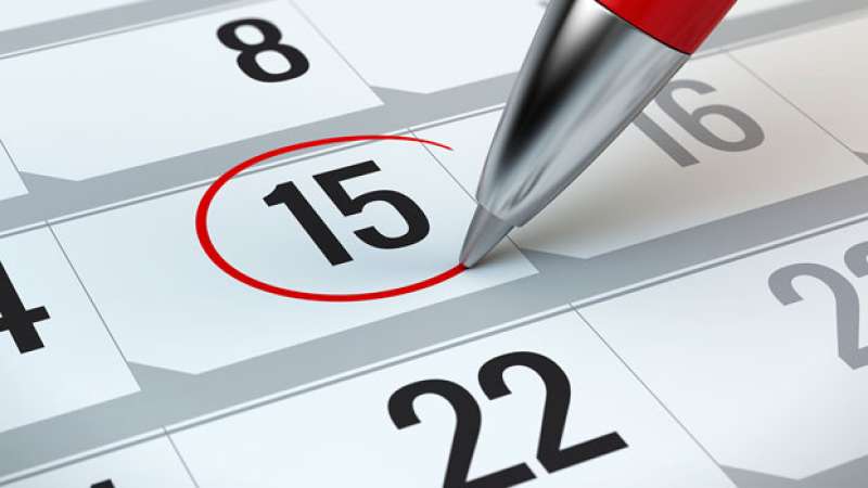 A pen is circling the 15th with a red pen on a calendar