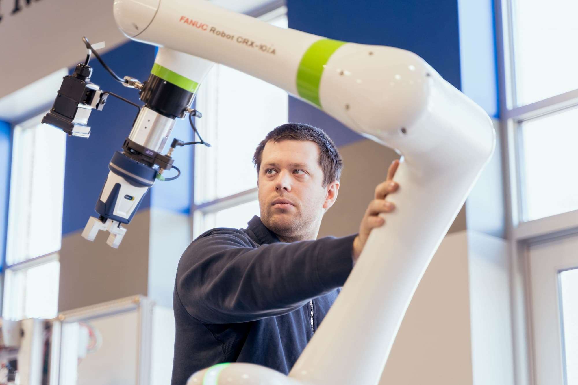 A man raises the position of a FANUC smart manufacturing robot.