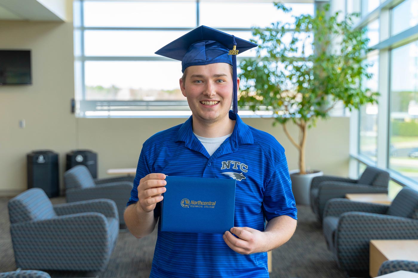 Alex posing while wearing an NTC graduation cap and holding his diploma