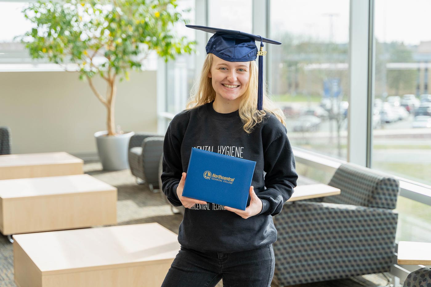 Marissa posing while wearing an NTC graduation cap and holding her diploma.