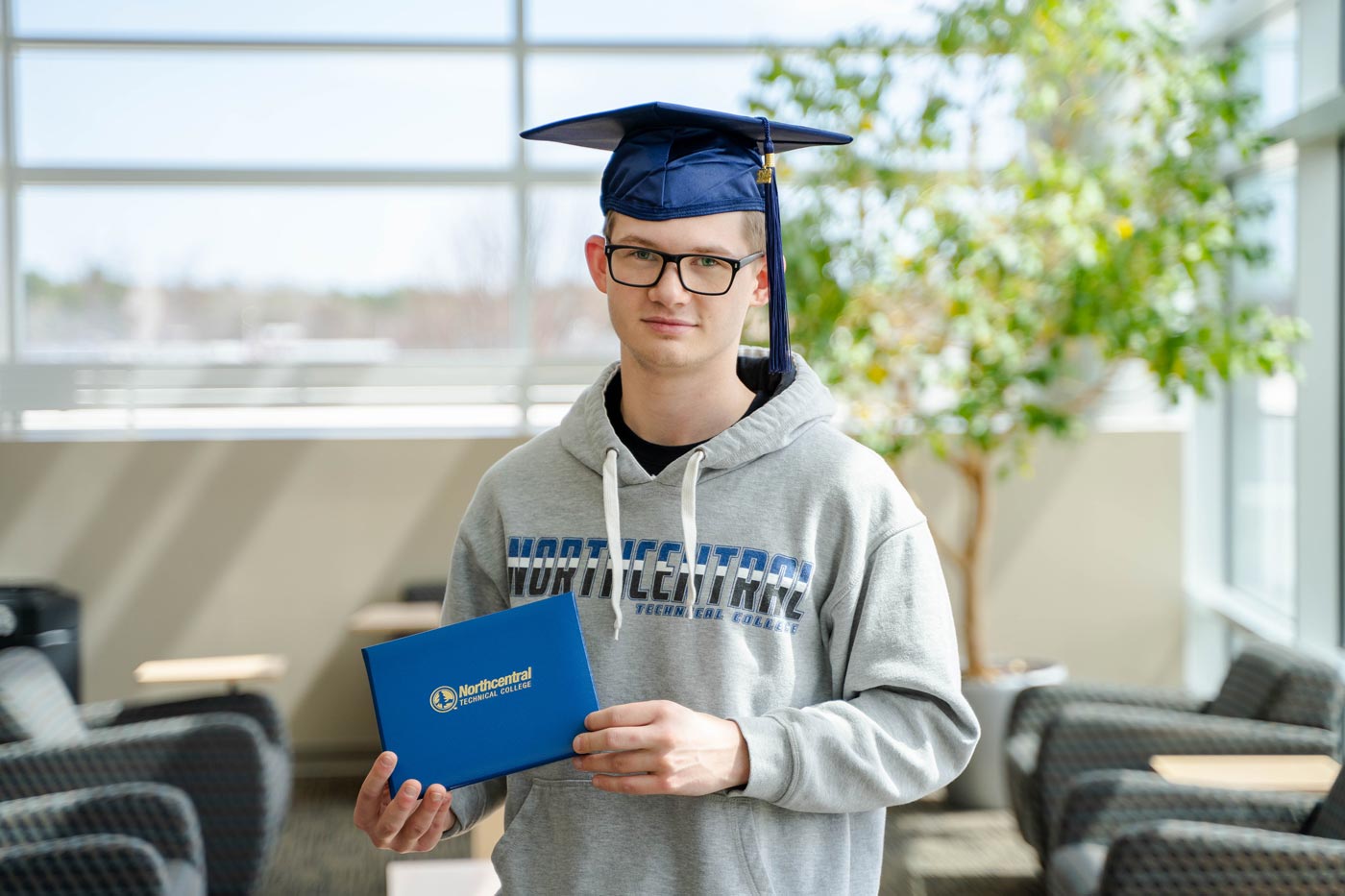 Nathan posing while wearing an NTC graduation cap and holding his diploma.