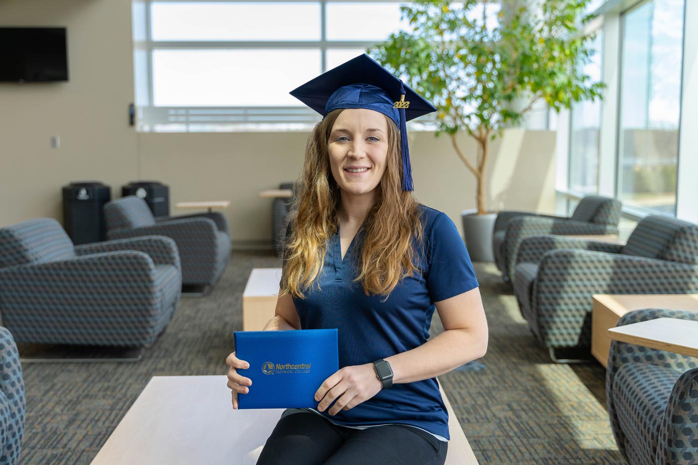 Victoria posing while wearing an NTC graduation cap and holding her diploma.