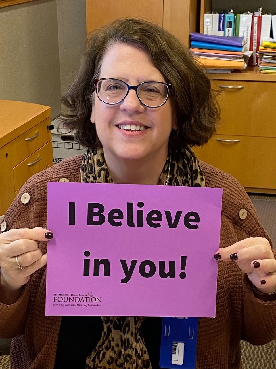 Jeannie Worden holding a sign that reads: I believe in you!