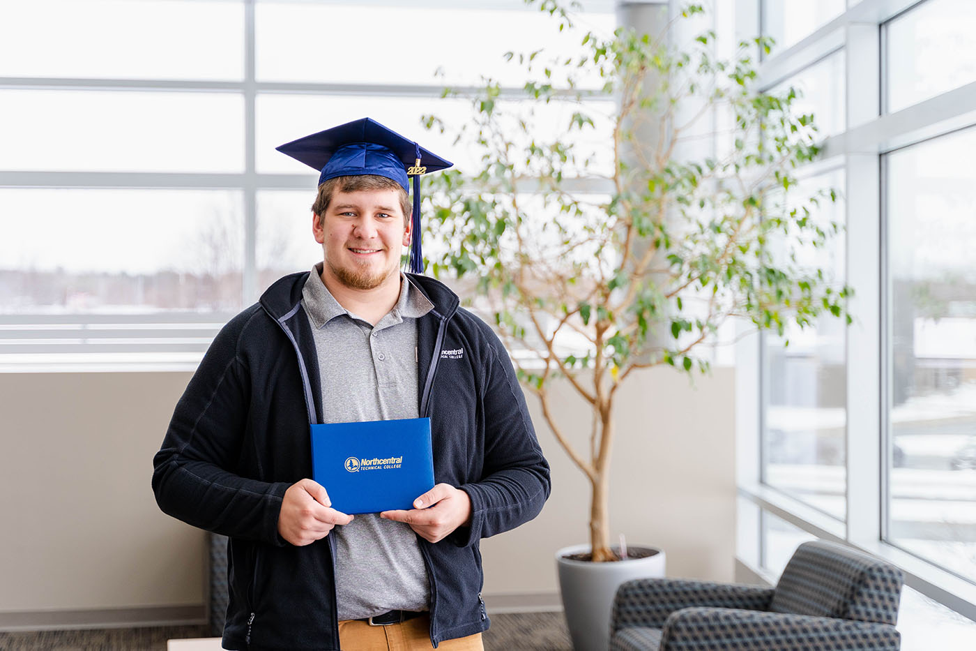 Jamieson posing while wearing an NTC graduation cap and holding his diploma.
