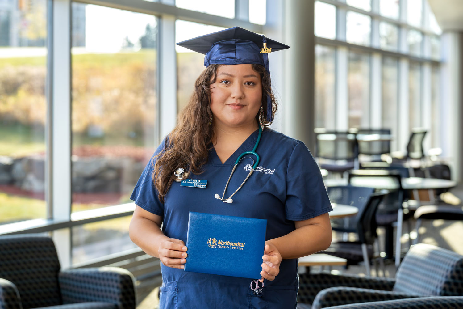 Alma posing while wearing an NTC graduation cap and holding her diploma.