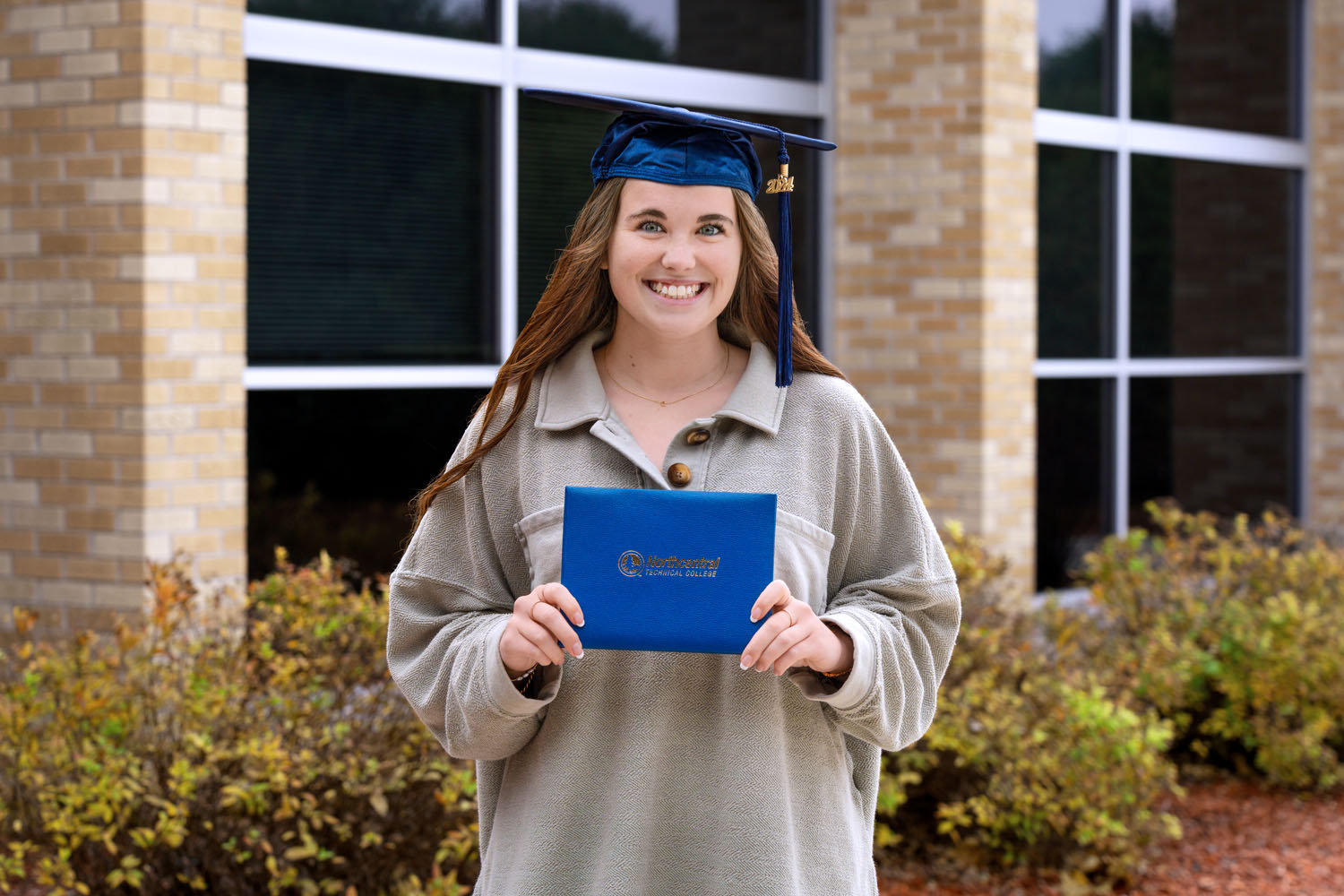 Celina posing while wearing an NTC graduation cap and holding his diploma.