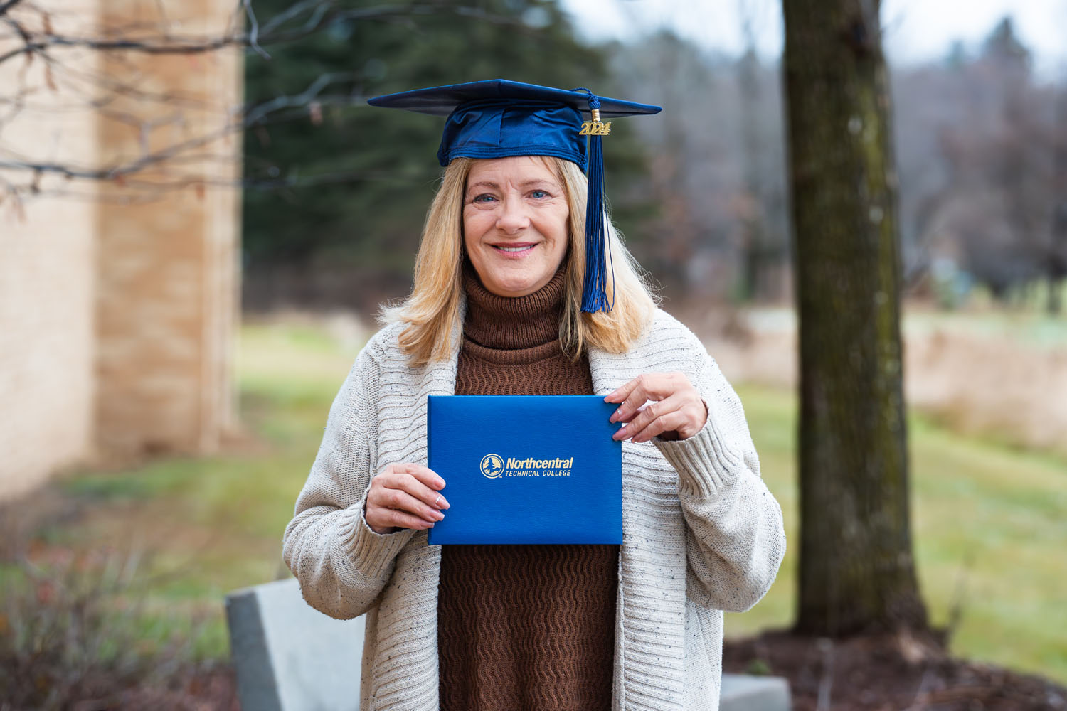 Jennifer posing while wearing an NTC graduation cap and holding her diploma.