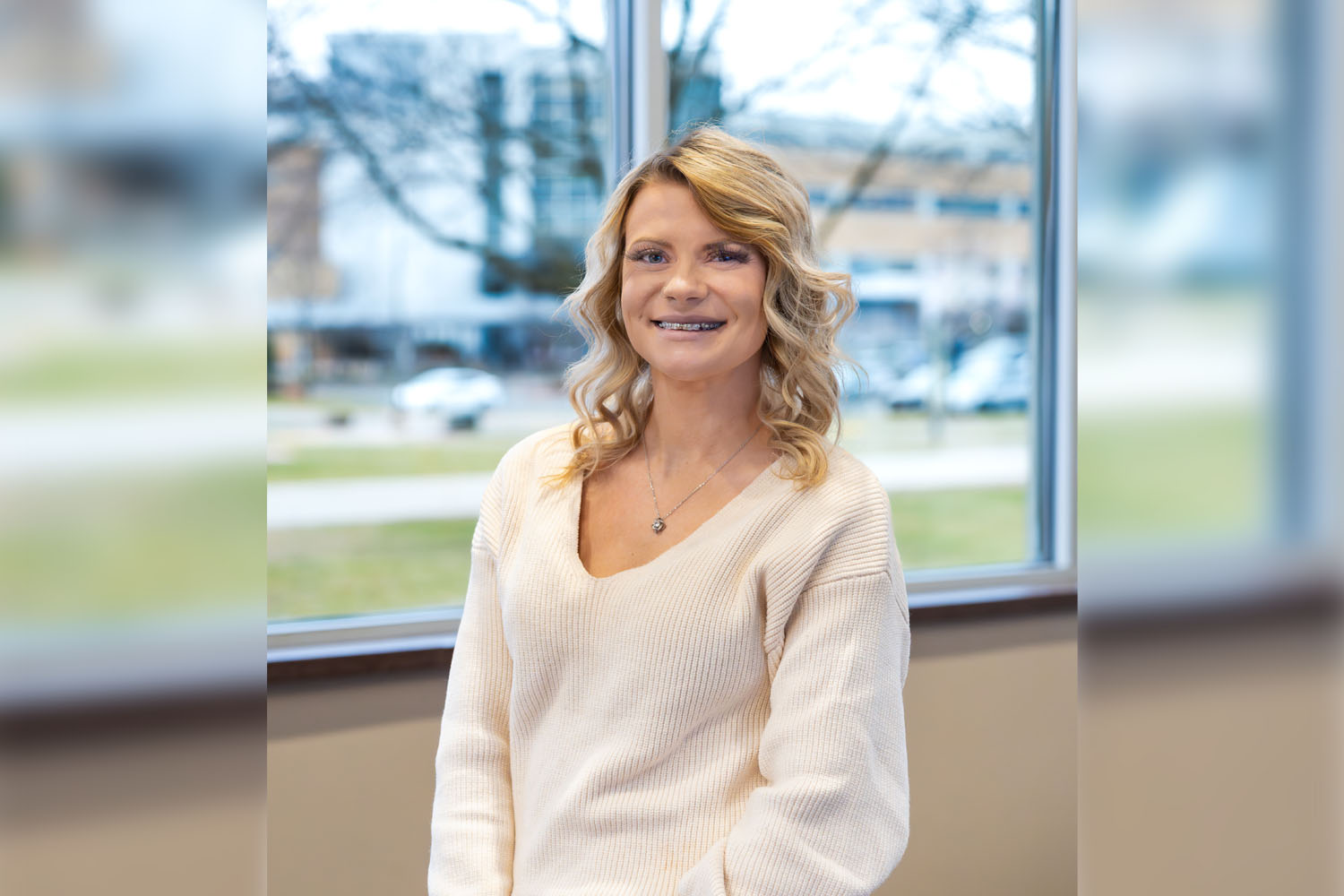 Kayla smiling while standing in front of a window inside the Wausau Campus