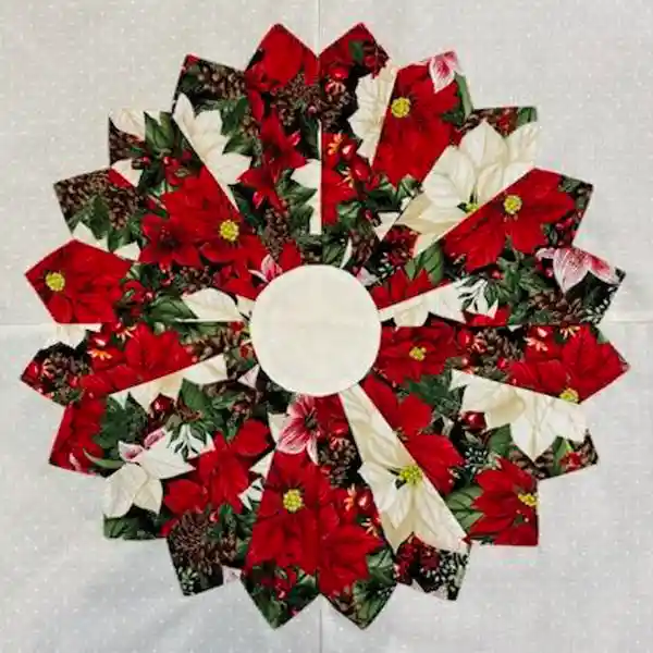Handcrafted circular quilted placemat featuring a festive pattern of red and white poinsettias, pinecones, and green leaves, with a plain cream center.