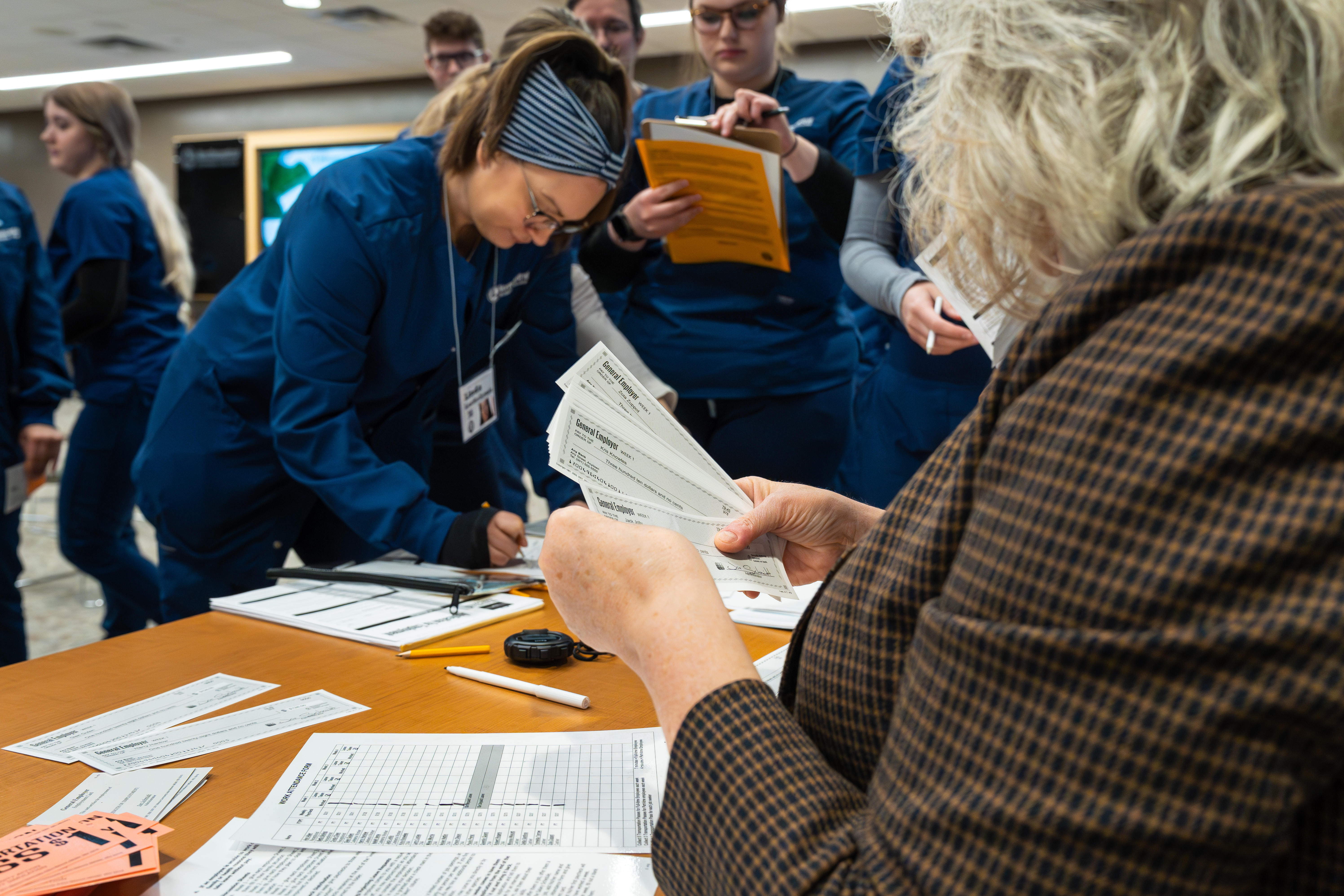 Nursing students holding clipboards and papers while participating in a poverty simulation.