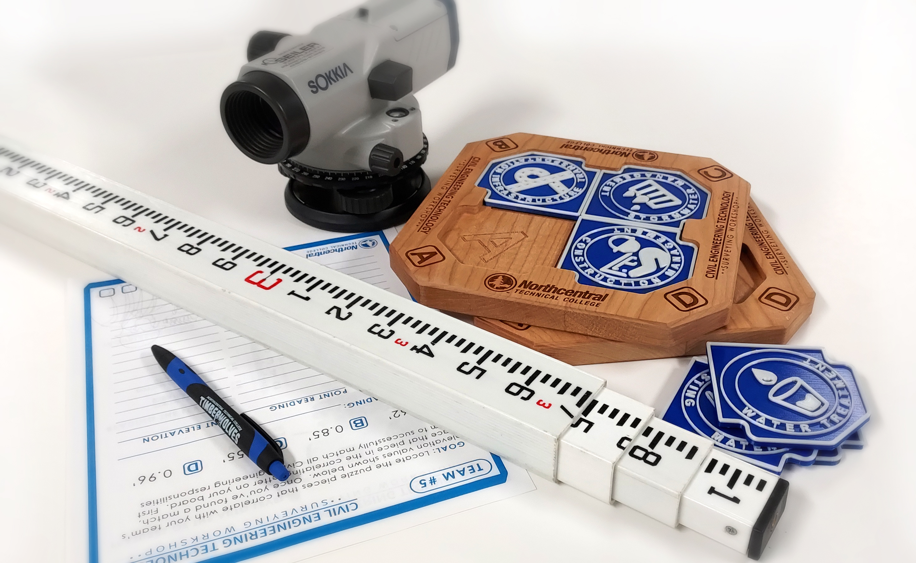 Surveying equipment, including an auto-level, set up indoors for a workshop activity.
