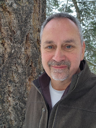Scott posing next to a tree outdoors