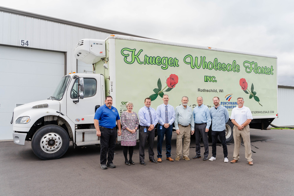 Several people stand in front of a truck with Krueger Florists Inc. written on the side.