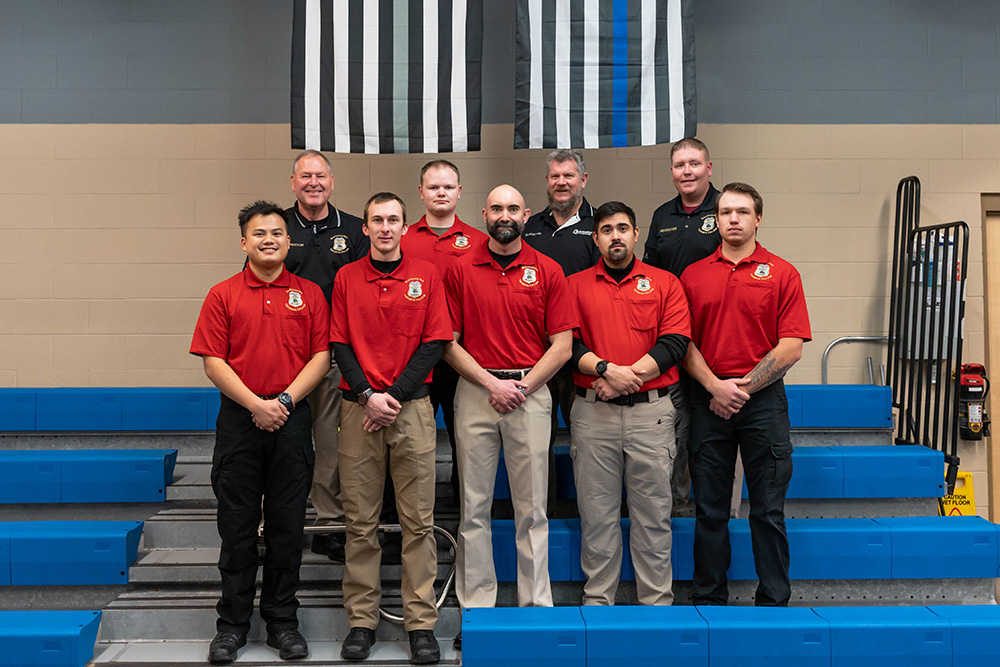 Leaders from NTC’s School of Public Safety stand with the graduates on a set of bleachers at the commencement ceremony.