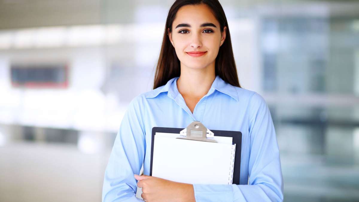 A woman stands with a clipboard in hand