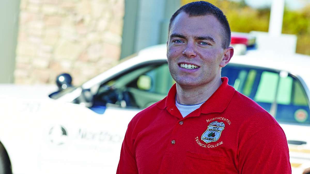 An NTC Security team member stands in front of a squad car