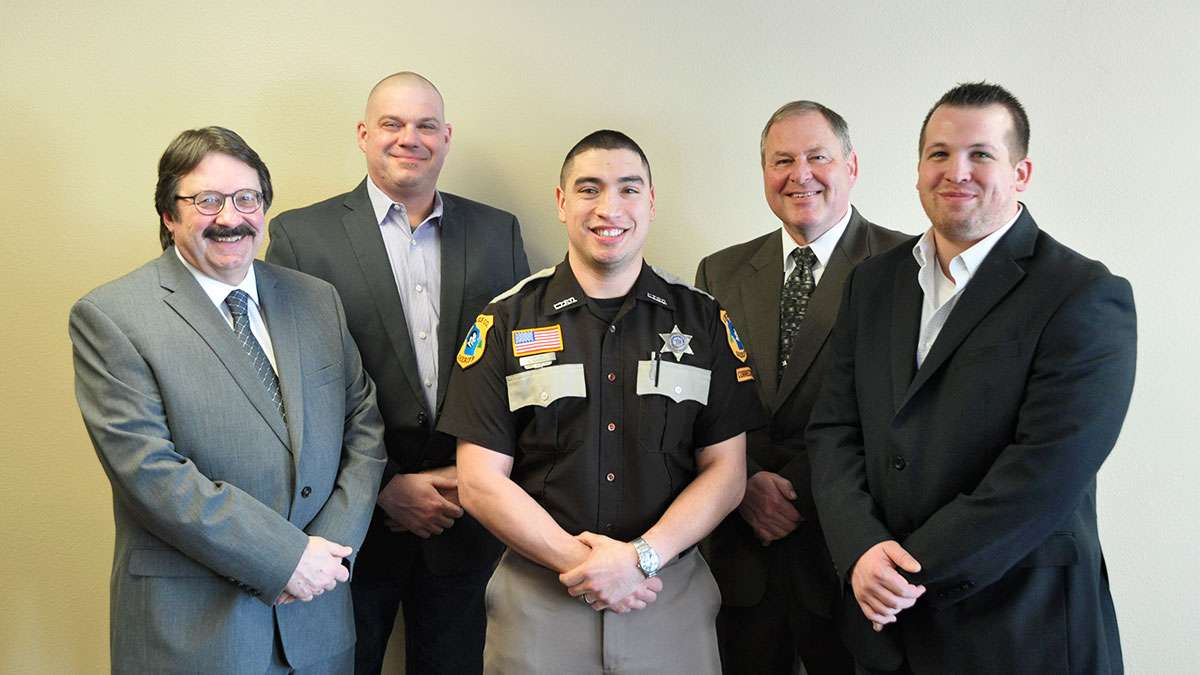 Jail Academy Graduate Rodriguez stands between his instructors