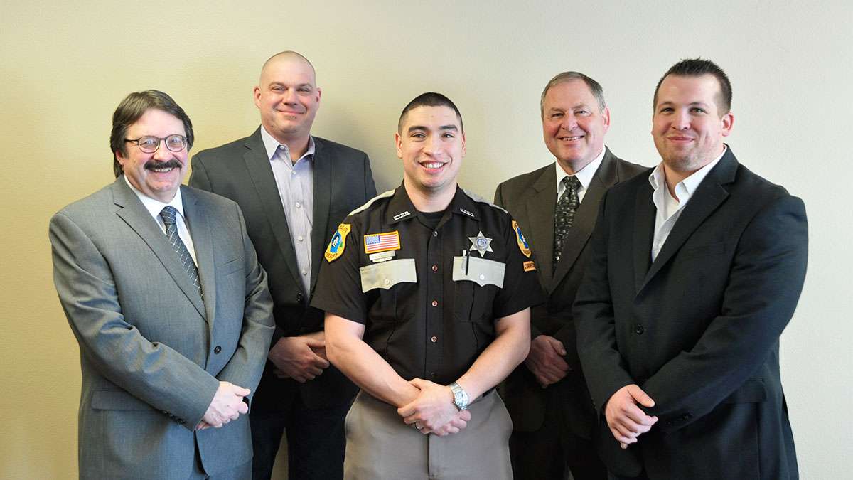 Jail Academy Graduate Rodriguez stands between his instructors