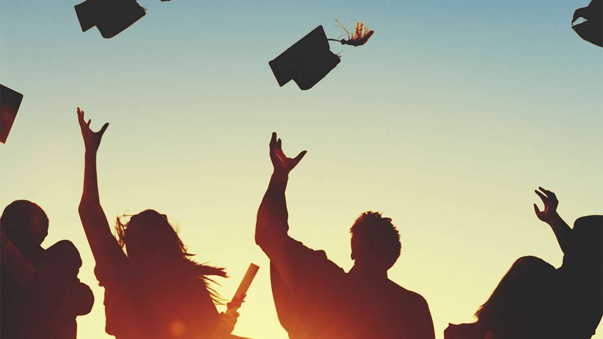 Several graduating students throwing their hats in the air