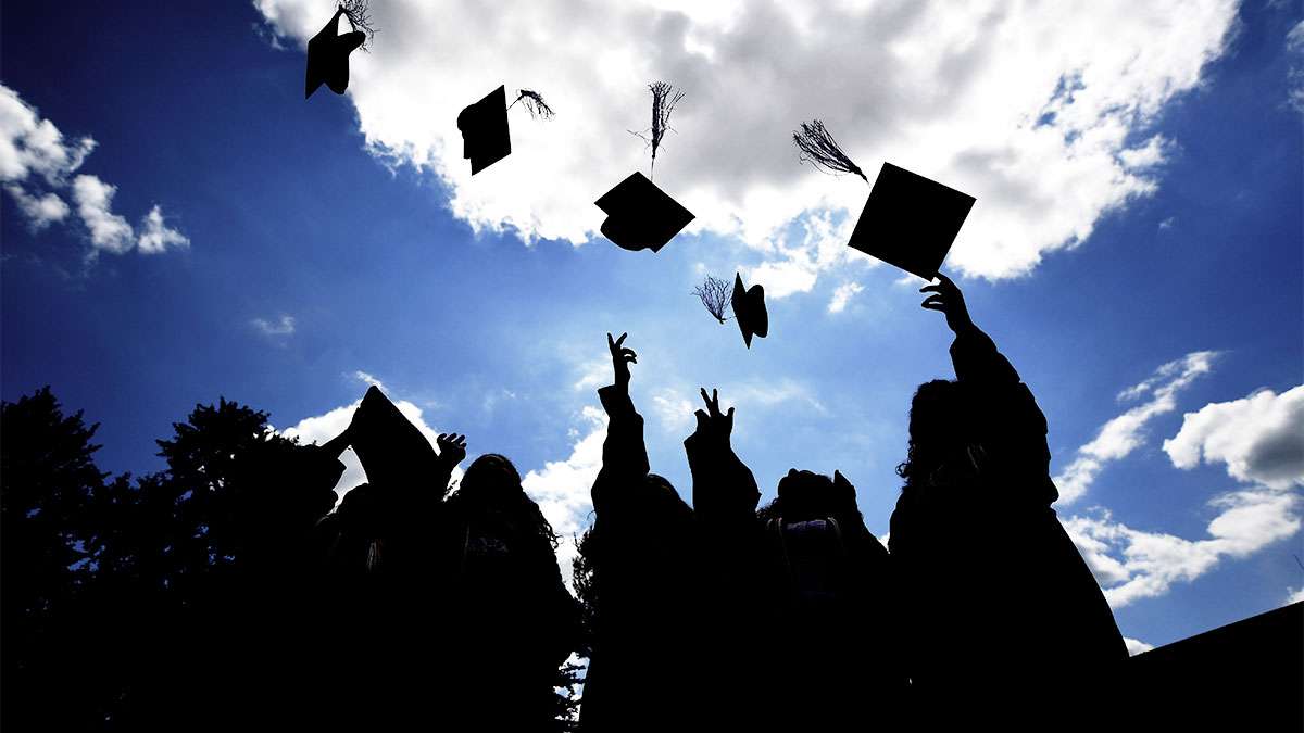 Several graduating students throwing their hats in the air