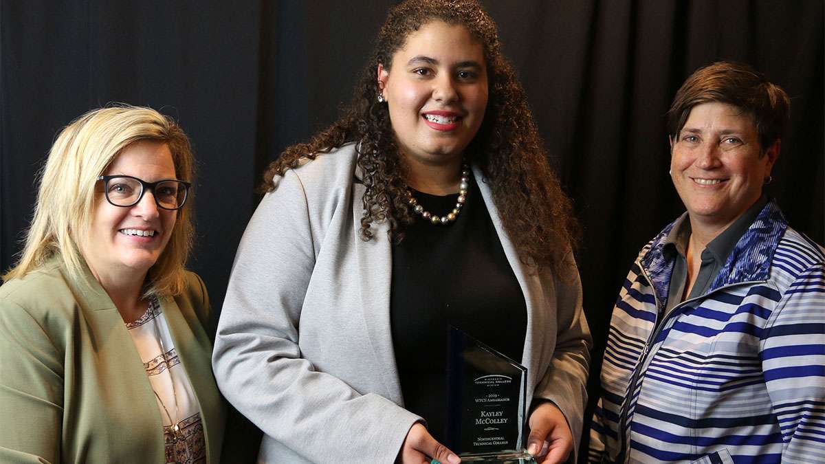 A student stands between two college instructors