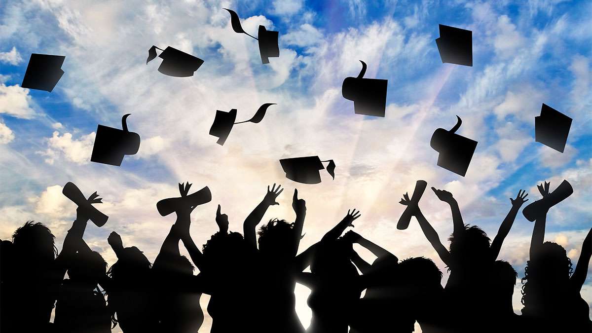 Several graduating students throwing their hats in the air