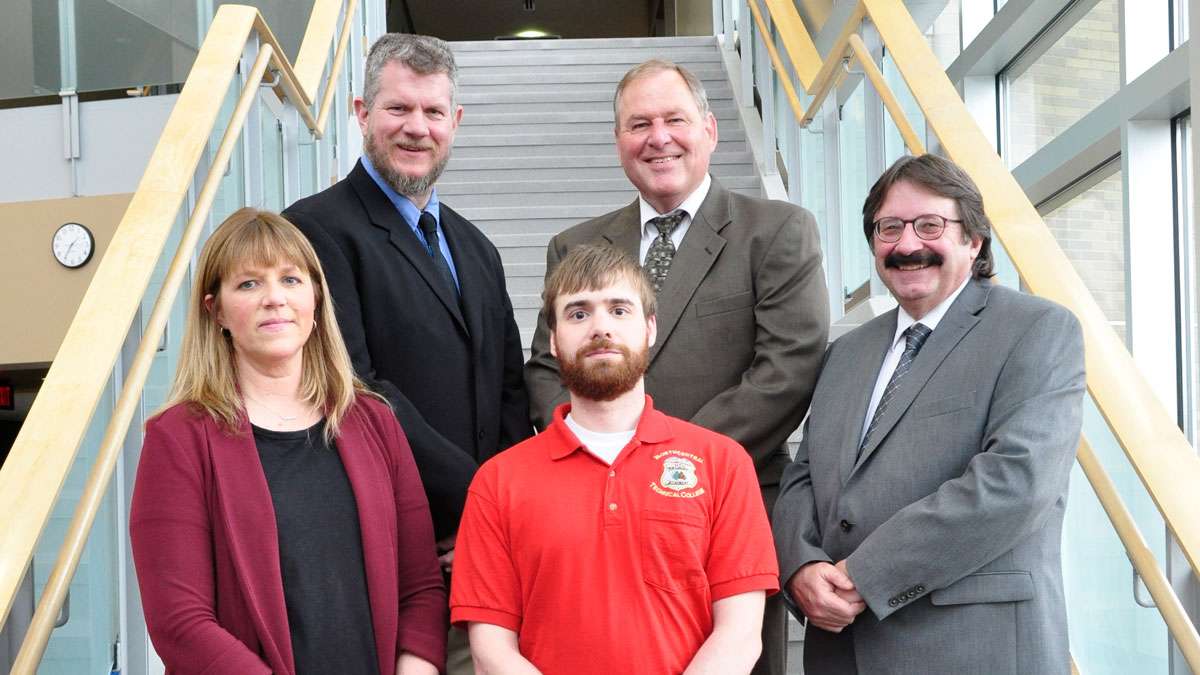 Ryan Eggers stands in front of his instructors on a staircase