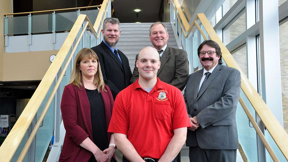 Paulson stands in front of his instructors on a staircase