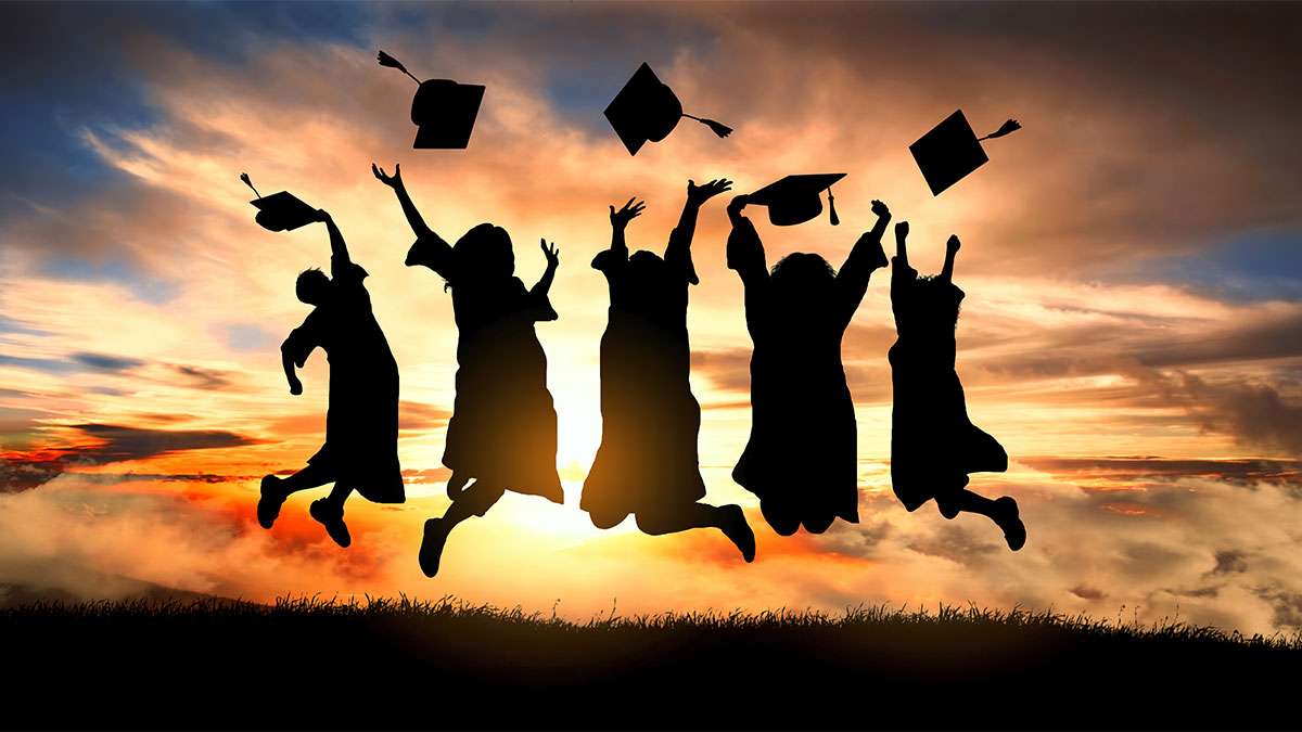 Graduating students jump up and throw their hats in the air.