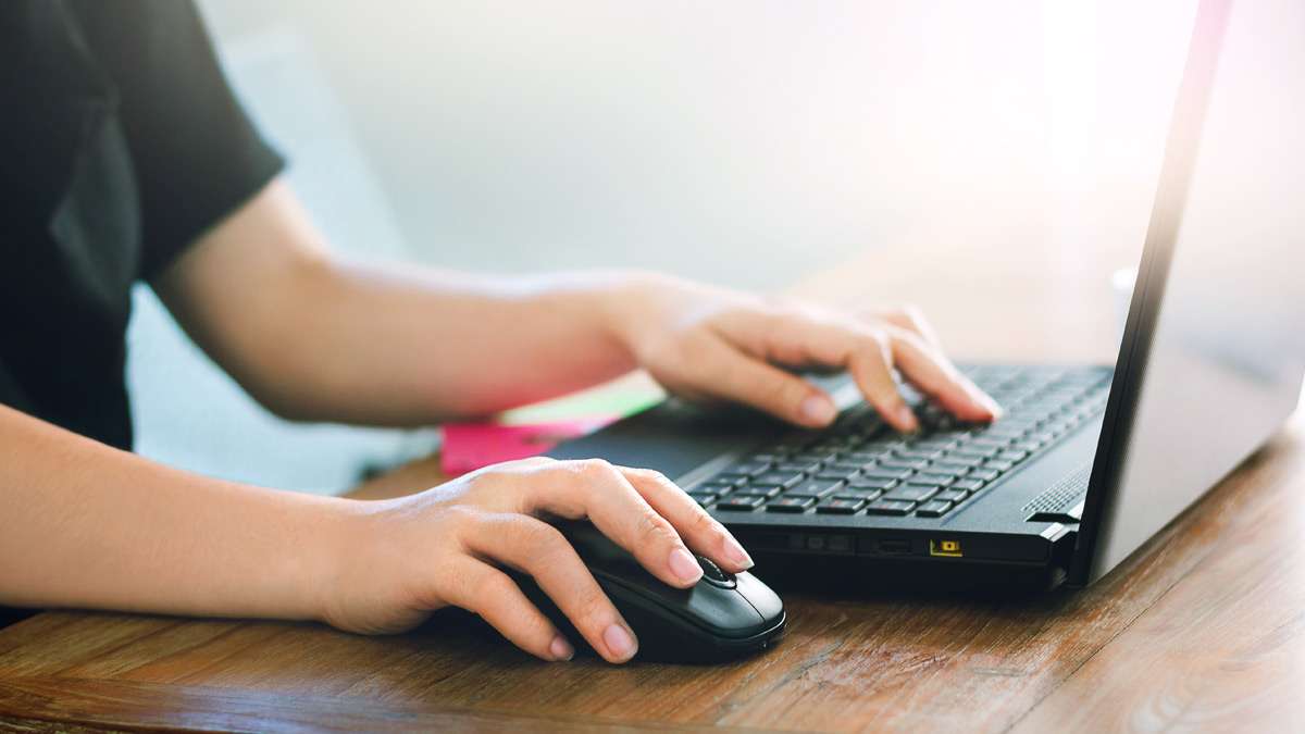 A person using a laptop on a wooden table