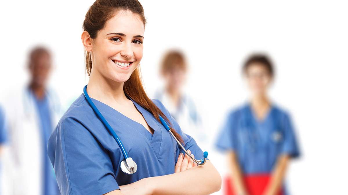 A young medical student stands with her arms crossed with a Stethoscope draped around her shoulders.