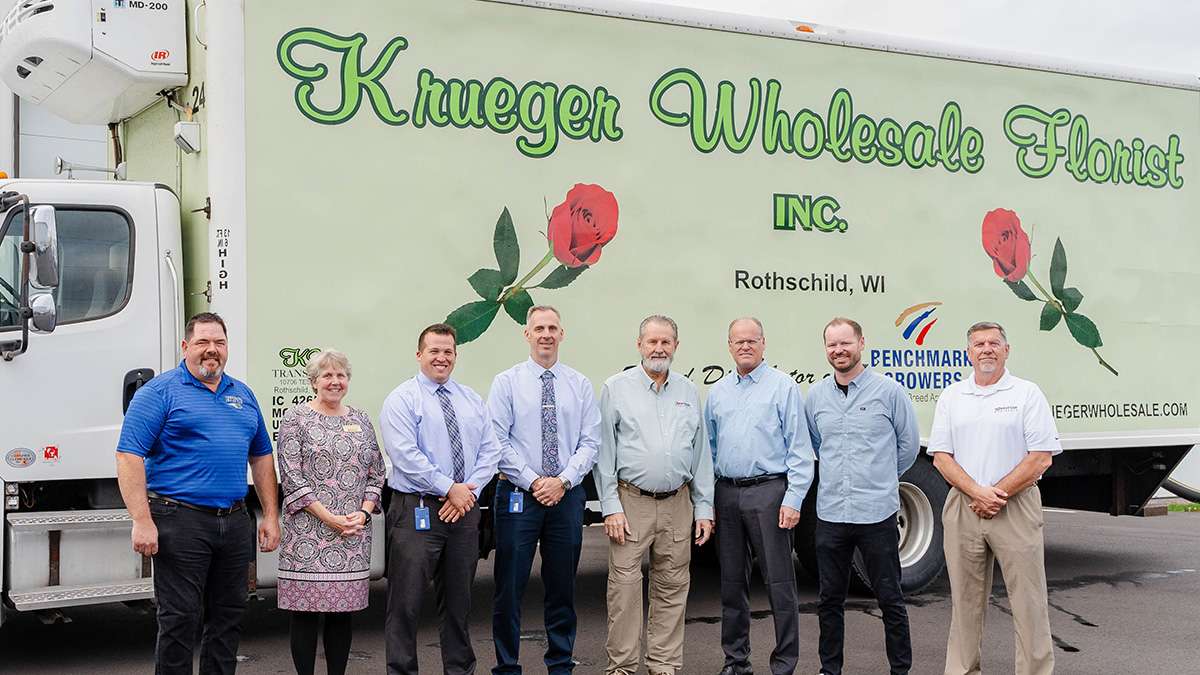 Several people stand in front of a truck with Krueger Florists Inc. written on the side.