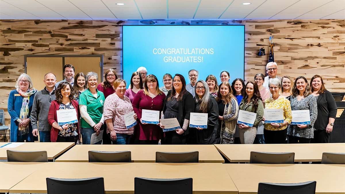 Graduates of Nonprofit Management Institute stand together with their certificates of completion at a graduation ceremony.