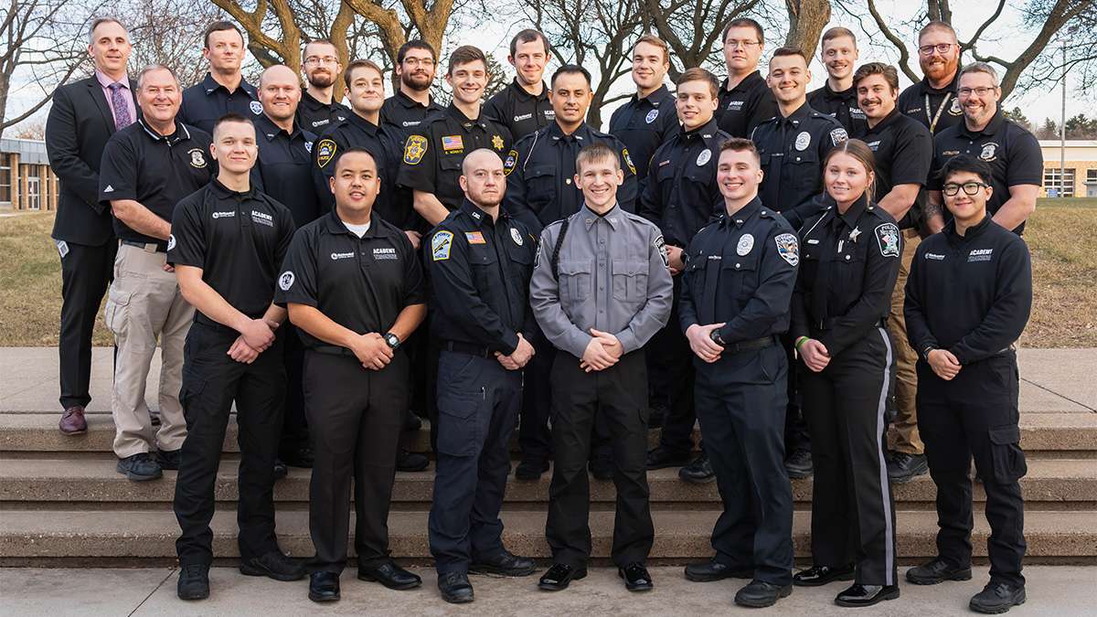 A group of Criminal Justice instructors and Criminal Justice graduates are standing together outside of NTC.