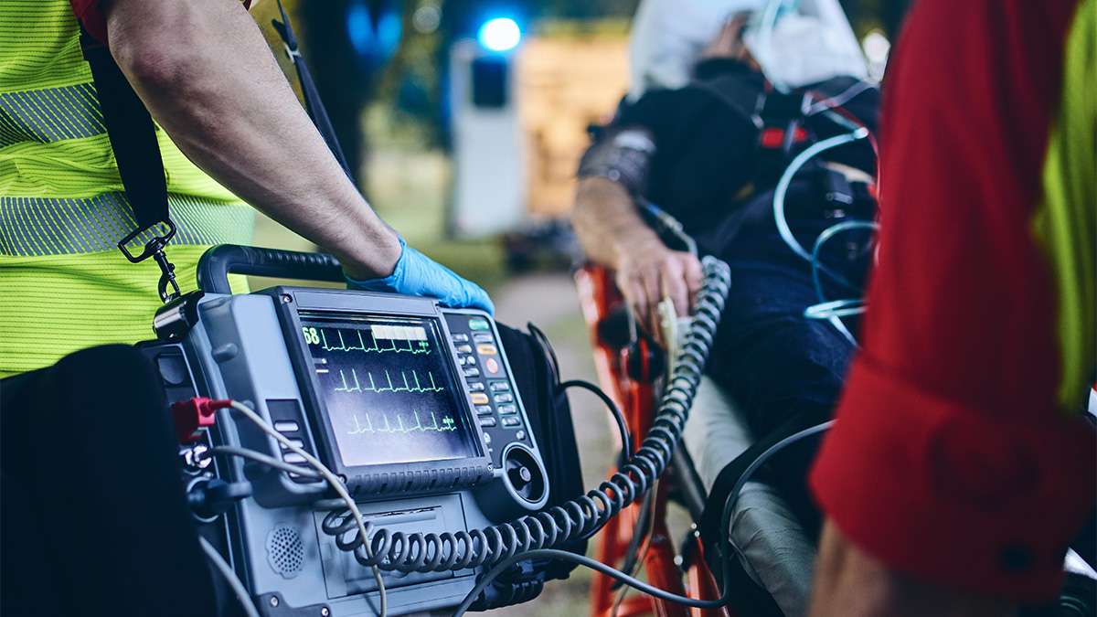 Emergency medical technician operates portable heart monitor during critical patient care scenario.