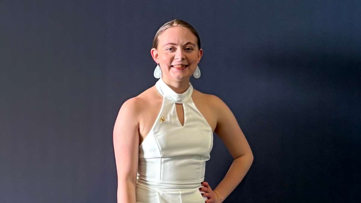 Emilynn smiling while standing in front of a dark gray backdrop.
