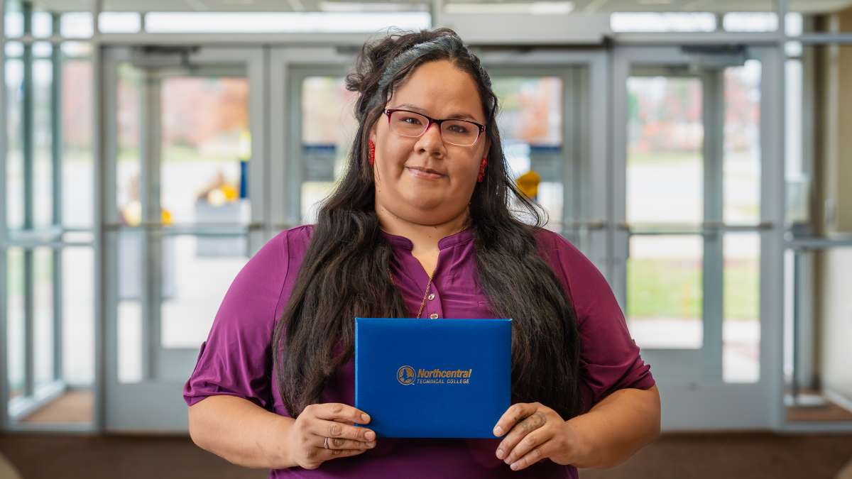 Jalissa smiling while holding her diploma.