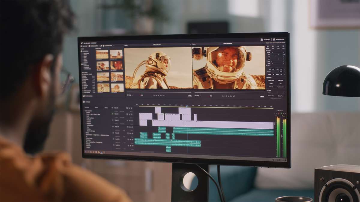 Bearded man seen from behind editing a space-themed video on a widescreen monitor, timeline and preview panels visible.