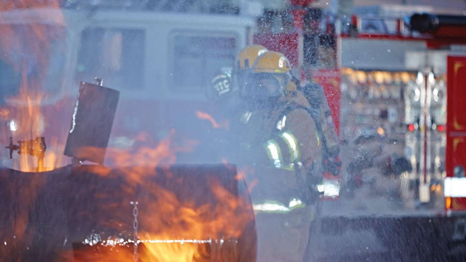 Fire Service students putting out a fire with a firetruck behind them.