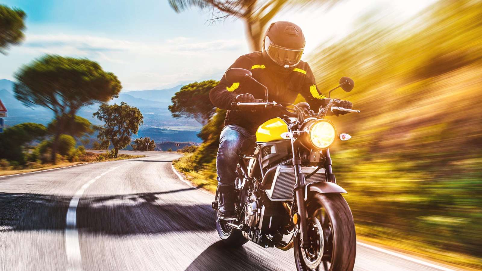 Motorcycle rider cruising around a curved road.