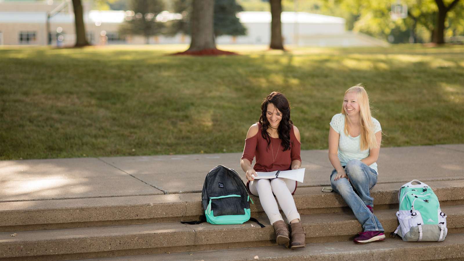 Two students sit together on some steps out in the Courtyard on the NTC Wausau Campus