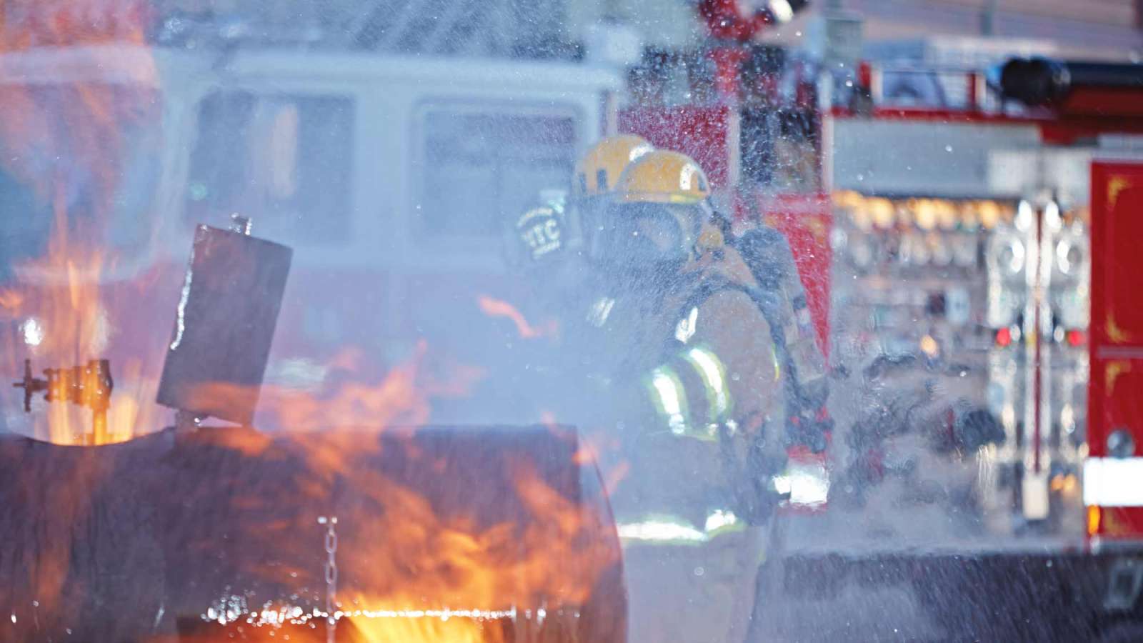 Firefighting training at the NTC Public Safety Center of Excellence, involving two trainees battling a blaze at a gas burn simulator.