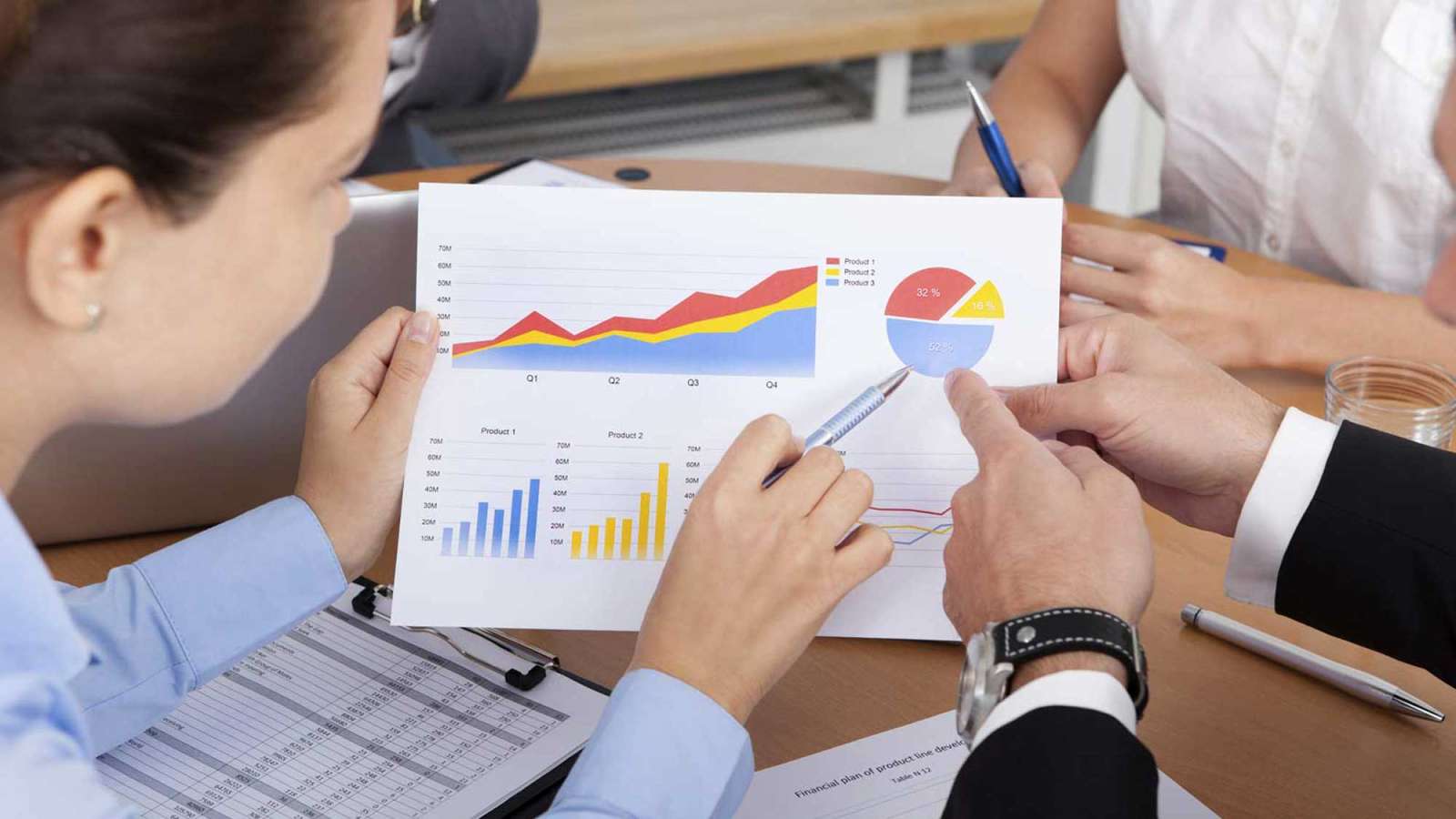 A group of business people look at some line, bar, and pie graphs.