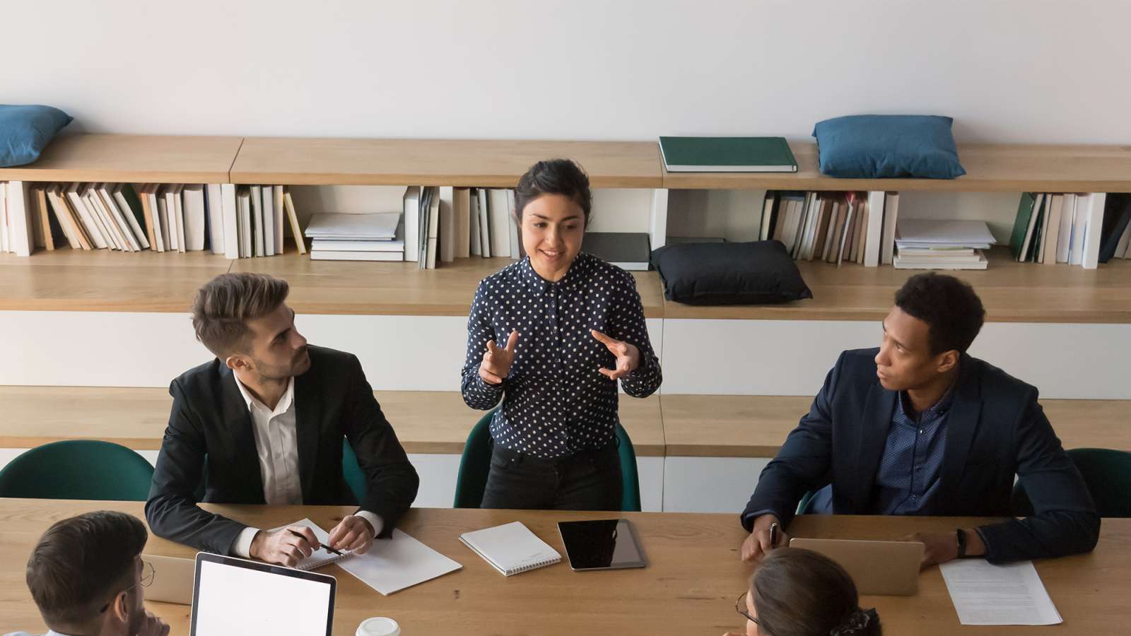 A supervier stands up at a meeting and talks to employees about ideas and concepts.