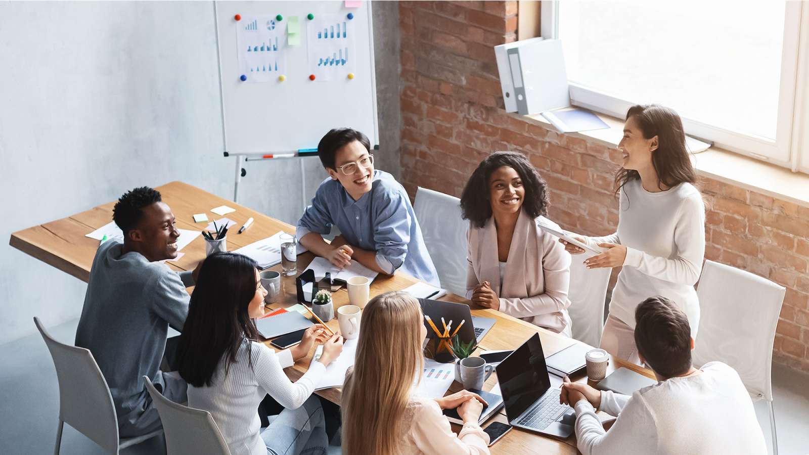 In an office, several business persons sit at a table discussing business.