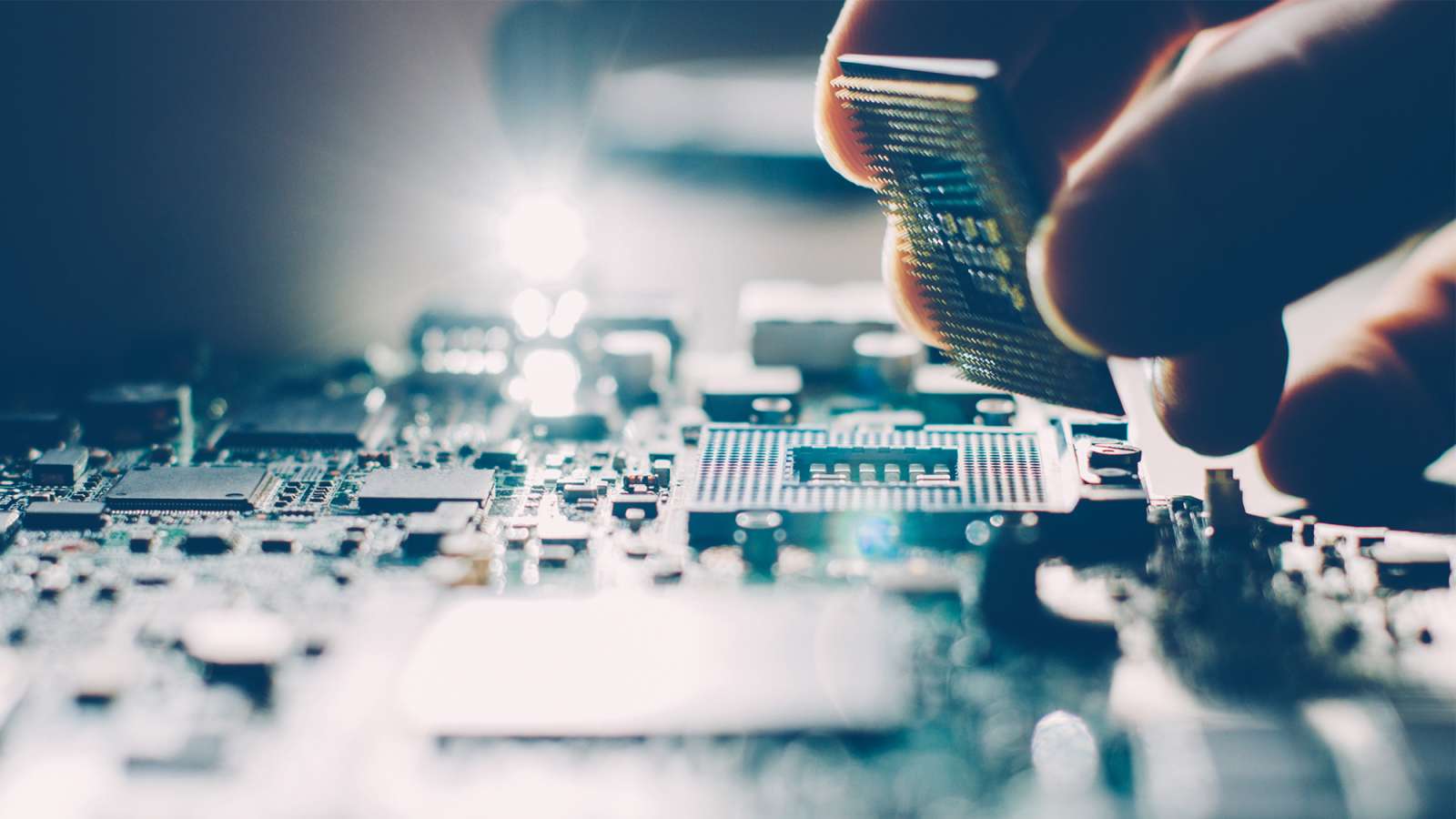 A computer support technician is placing a computer processor into the processor socket on a motherboard.