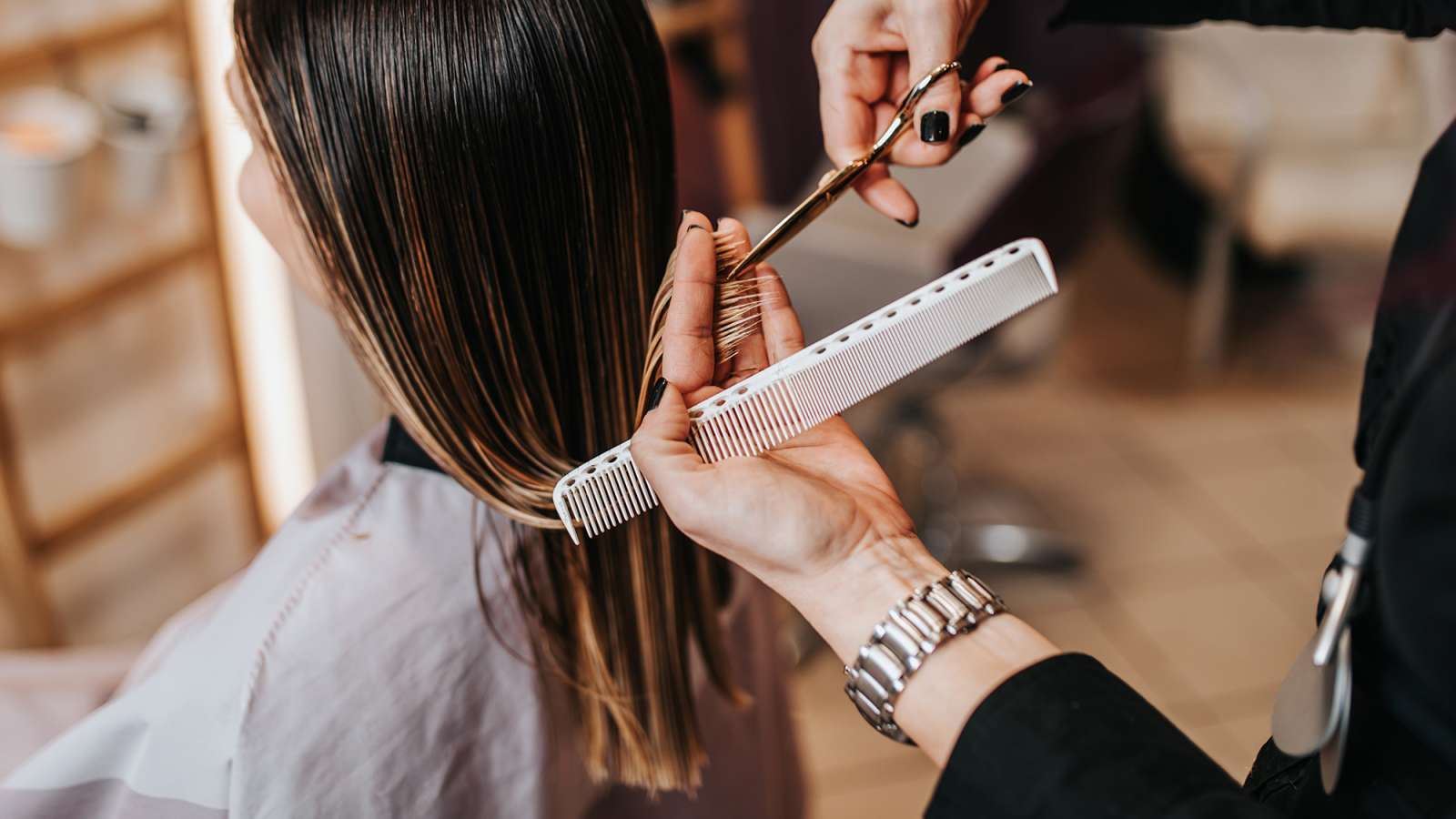Young woman getting her haircut by a hairstylist at a beauty salon.