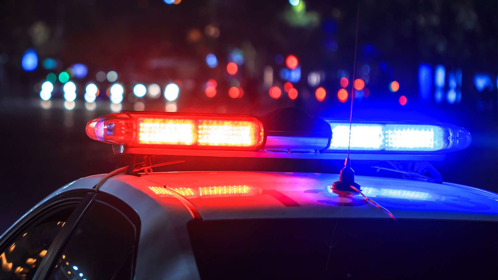 An external side view of a police car at night with the flashing lights turned on.
