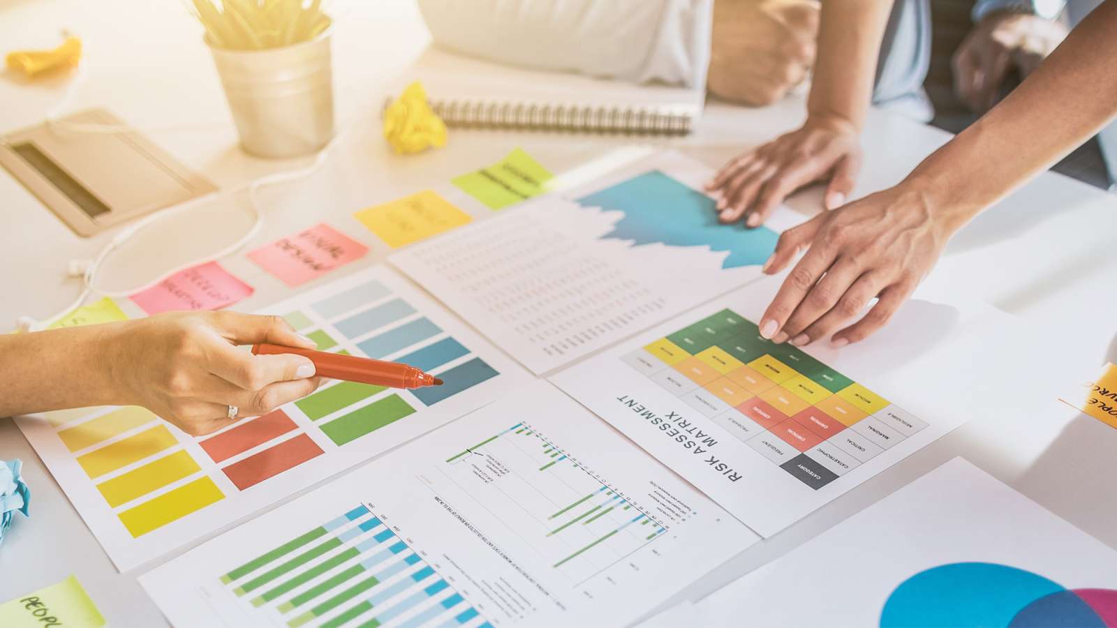 Creative business persons are having a meeting around a table while discussing data from charts and graphs.
